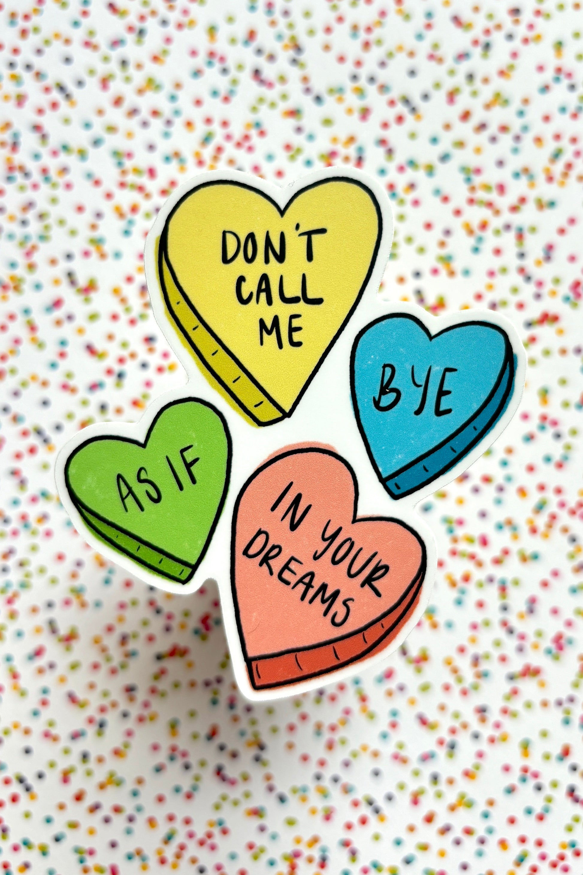 Colorful heart-shaped pins with text on a multicolored confetti background