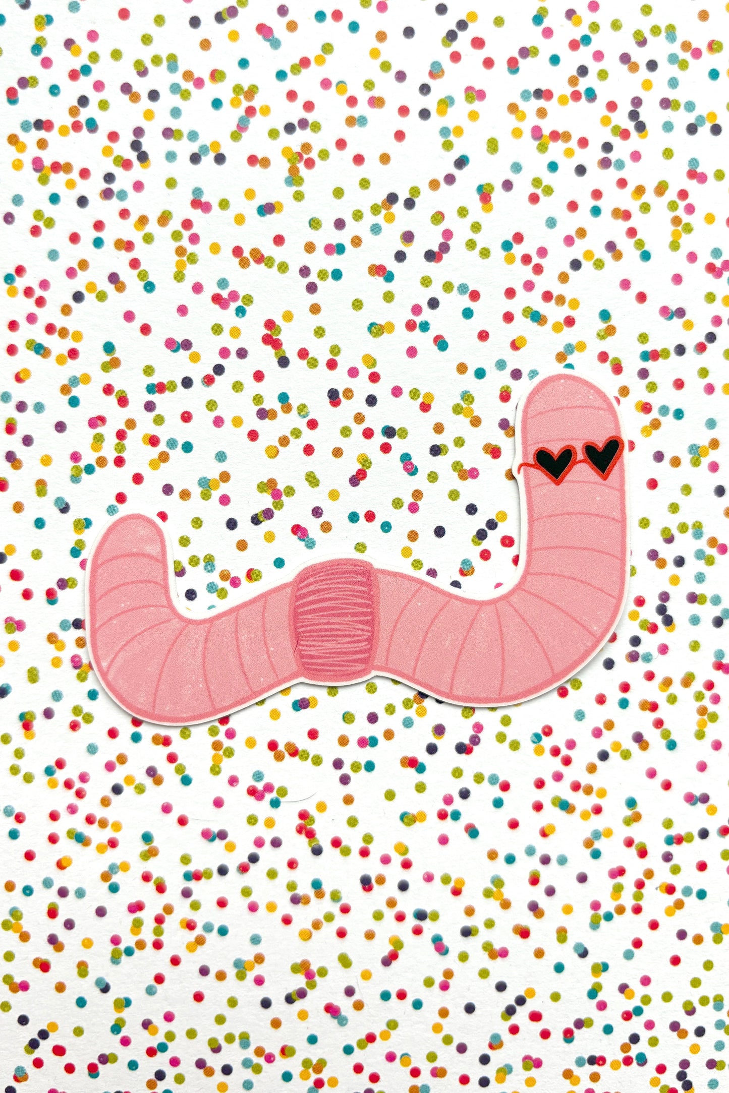 Pink worm with heart eyes on a white background with colorful confetti